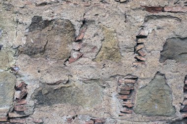 Kadim el yapımı taş duvar. Çok renkli açıkta kalan taş, tuğla ve mineral tabakası. Taş deseni, jeolojik doku. Parlak kırmızı-kahverengi taş arka plan. Soyut arkaplan.