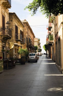 Santo Stefano di Camastra, İtalya-27 Ekim 2023 oldukça dar bir kaldırım taşı caddesi. Tipik İtalyan caddesi. Konut binaları, küçük restoranlar ve açık hava kafeleri var. Seyahat ve turizm kavramı.