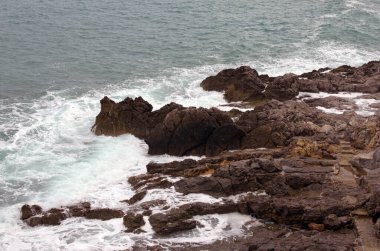 Kayalık bir yamacın manzaralı deniz manzarası ve İtalya 'nın Sicilya kenti Cefalu yakınlarındaki Tyrhenian denizinin turkuaz su dalgalarına kayalıklar. Deniz ve kayalar. Doğal bileşim. Seyahat ve turizm kavramı.