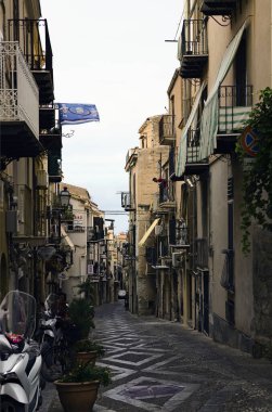 Cefalu, İtalya-28 Ekim 2023: Eski konutlar arasındaki otantik dar kaldırım taşı caddesi. Ortaçağ Cefalu 'sunda geleneksel cadde. Seyahat ve turizm kavramı.