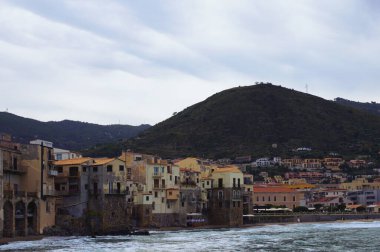 Antik Cefalu şehrinin şaşırtıcı panoramik kıyı manzarası. Kumsaldaki renkli binalar. Huzurlu su dalgaları duvarlara çarpıyor. Tyrhenian Denizi, Cefalu, Sicilya, İtalya.