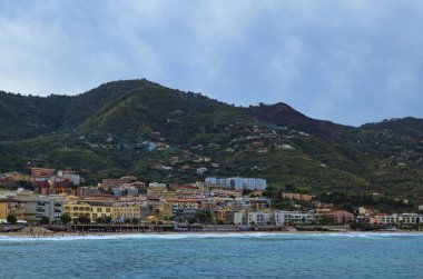 Şehir plajının dinlenen insanlarla manzarası. Bulutlu hava, Tyrhenian Denizi 'nde dalgalar. Arka planda şehir manzarası. Seyahat ve turizm kavramı.