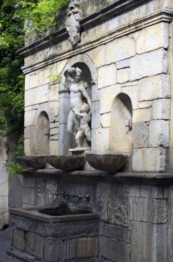 Castelbuono, İtalya-28 Ekim 2023: Castelbuono köyünde çok sayıda süs ve heykel bulunan antik taş içme çeşmesi. Sicilya, İtalya. Islak yüzeylerde büyüyen siyah küf ve yeşil yosun..