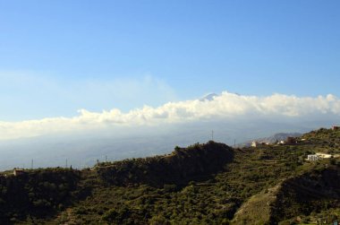 Panoramik doğa manzarası. Dağlar mavi gökyüzüne karşı. Arka planda beyaz bulutlar içinde ünlü Sicilya Etna volkanı. Taormina 'dan görüntü. Seyahat ve turizm kavramı.