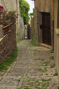 İtalya 'nın Sicilya kentindeki Erice köyünün tarihi bölümündeki antik binalar boyunca uzanan tipik bir orta çağ kaldırım taşı caddesinin manzarası. Seyahat ve turizm kavramı.