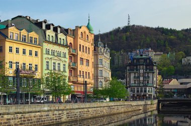 Karlovy Vary, Çek Cumhuriyeti-Nisan 09.2024: Karlovy Vary 'deki eski kasabanın panoramik şehir manzarası. Tepla nehrinin kaldırım taşı seti ve nehir boyunca renkli binalar. Seyahat ve turizm kavramı.