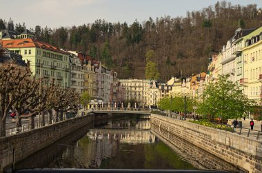 Karlovy Vary, Çek Cumhuriyeti-Nisan 09.2024: Karlovy Vary 'deki eski kasabanın panoramik şehir manzarası. Tepla nehrinin kaldırım taşı seti ve nehir boyunca renkli binalar. Seyahat ve turizm.