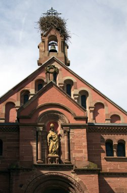 Scenic landscape photo of ancient St. Leon Church in Eguisheim, France. Blue sky background. Sunny spring day. The chapel is dedicated to Pope Saint-Leon IX. Popular tourist destination in Eguisheim. clipart