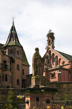 Eguisheim, Fransa-11 Nisan 2024: Eguisheim köyündeki ortaçağ Saint-Leon Meydanı. Papa Saint-Leon X. Heykel. Arka planda St. Leon Kilisesi var. Eguisheim 'ın önemli bir simgesi.