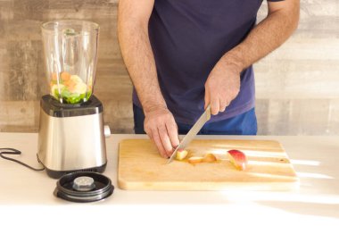 Genç adam mutfakta sağlıklı salata hazırlıyor.