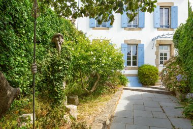 Auray 'da bir kır evi. Yoldan sakin bir manzara ve bahçede bir sanat eseri..