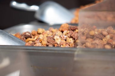 A view of several trays of roasted assorted nuts, on display at a food vendor.