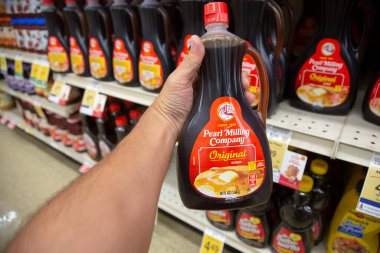 Los Angeles, California, ABD - 05-20-2022: Yerel bir bakkalda sergilenen Pearl Milling Company şurubu şişesini tutan bir elin görüntüsü.