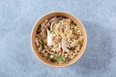 Tavuklu ve pirinçli bir yemeğin konteynıra konulacağı kâğıdın yukarıdan görünüşü..