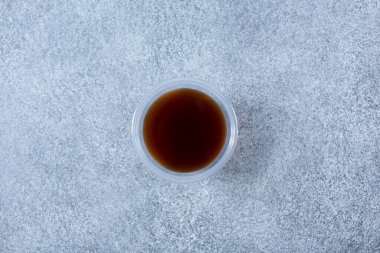 Kahverengi bir sosun plastik bir çeşni kabının yukarıdan görünüşü.