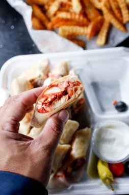 Tavuklu shawarma dürümü tutan bir elin görüntüsü.
