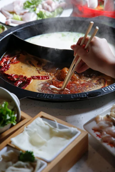 鍋料理のすべての要素で見られるスープボウルに生の肉スライスを浸漬ビューの手 — ストック写真