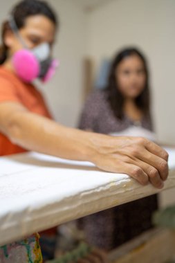 Bir atölyedeki sörf tahtasının yüzeyini ölçen bir uzmanlığın dikey fotoğrafı