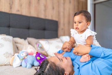 Meraklı bebek, annesiyle yatakta oynarken yüzen bir baloncuğa bakar..