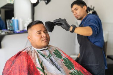 Berber, bir müşterinin sakalını temizlemek için fırça kullanıyor.