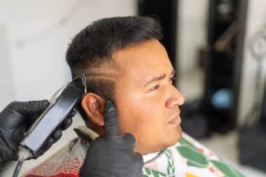 Berber elektrikli jiletle müşterinin saçıyla şekiller yaratıyor.