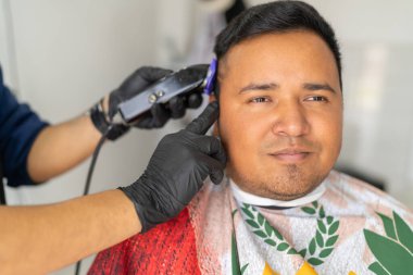 Elektrikli jilet kullanan bir müşterinin saçını kesen tanınmamış berber.