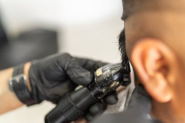 Latin bir müşterinin saçını kesmek için jilet kullanan bir berbere yakın plan.