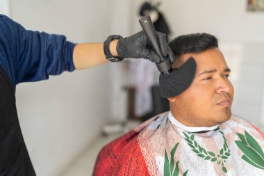 Berber, saçını kestikten sonra bir müşterinin yüzünü fırçayla temizliyor.