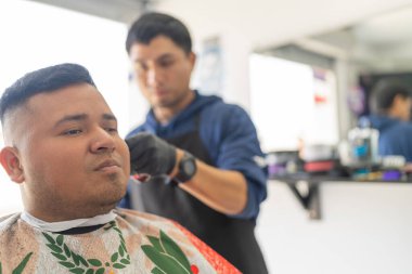 Berber dükkanında saçını keserken oturan tatmin olmuş latin adam.