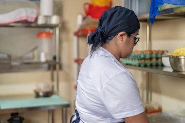 Mutfakta çalışmaya hazır tanınmayan bir kadın aşçının yan görüntüsü.
