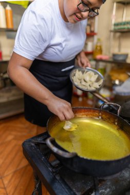 Kızartmak için yağlı bir tavaya Wonton koyan bir şefin dikey fotoğrafı.