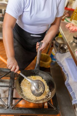 Peru 'da bir restoranda şoför hazırlamak için pirinç kaldıran bir şefin dikey görüntüsü.