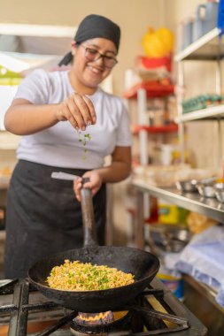 Gülümseyen bir şefin dikey fotoğrafı baharatlı noddles Bir restoranda kızartma tavasında