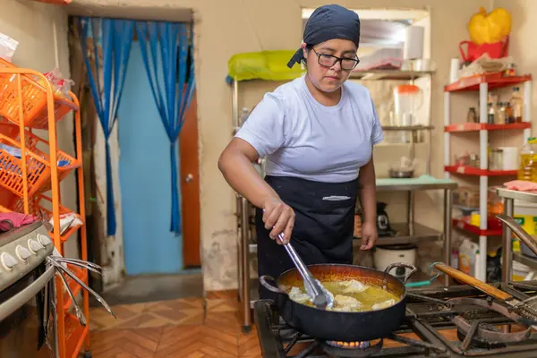 Peru restoranının mutfağında mantı kızartan kadın aşçı.