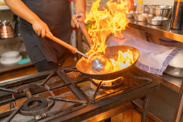 Tanınmayan bir şefin yakın plan fotoğrafı. Tavada yanan malzemeler.