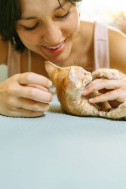 Gülümseyen bir kadının kızıl bir kediyi gıdıkladığı neşeli ve sevgi dolu bir bağ kurduğu çekici bir sahne..