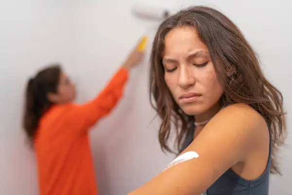Angry young woman because she has stained herself with paint while painting the house with a friend