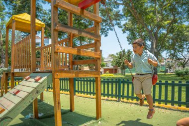 Okuldan sonra parkta sallanan Latin bir çocuğun fotokopi çekilen yatay fotoğrafı.