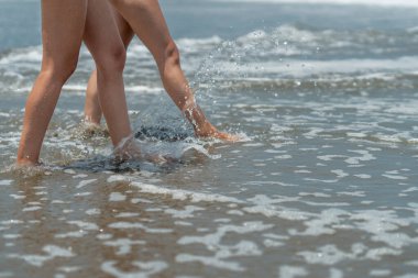 Deniz kıyısında çıplak ayakla yürüyen kadınların bacaklarının fotokopi aletiyle yatay fotoğraf.
