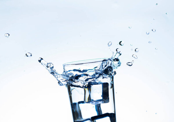 Изображение заливки питьевой воды в стакан, который заставляет чувствовать себя освеженным на размытом белом фоне, брызги воды, газированная вода