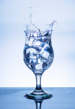 Kırık bir bardağa su dökme görüntüsü, bulanık beyaz arka planda ferahlama hissi verir, su sıçratma, köpüklü su, tehlike ya da yakın tehlike kavramı.