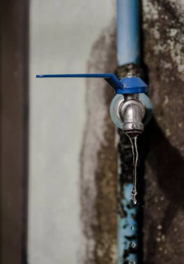 Su israfı - musluktan su damlası, sızıntı ya da musluk, uzak bölgedeki su musluğu, köydeki herkesin içmek için kullandığı kurumuş ve kirli musluk, uzak bir bölgede bulunan, devlet kurumlarının su tesisatının yetersizliğini yansıtıyor.