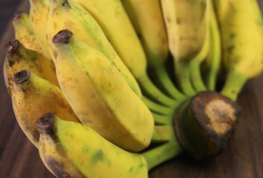 Bulanık arkaplanda ahşap masa olan muz meyvesi.