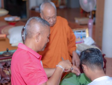 Bangkok, Tayland - 26 Mart 2021 Budizm 'e olan inanç ilkelerine göre genç bir adamın kafasını tıraş etmek için bir araya gelirler.