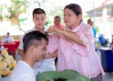 Bangkok, Tayland - 26 Mart 2021 Budizm 'e olan inanç ilkelerine göre genç bir adamın kafasını traş etmek için bir araya gelirler.
