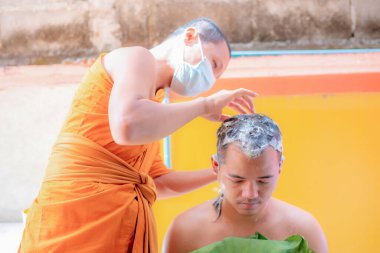 Bangkok, Tayland - 26 Mart 2021 Budizm 'e olan inanç ilkelerine göre genç bir adamın kafasını tıraş etmek için bir araya gelirler.