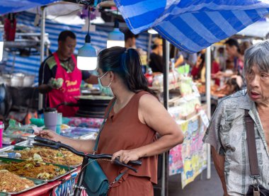 Suratthani, Tayland - 21 Nisan 2024: Yemek ve sebze almak için sokaklarda yürüyen insanlar, hem Tayland 'ın şehir ve kırsal kesimlerinde hem de sokak yemeklerinde yol kenarında satılıyor.