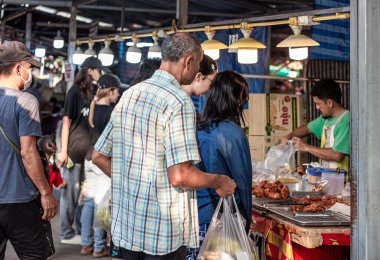 Suratthani, Tayland - 24 Nisan 2024: Hem Tayland 'ın kırsal kesimlerinde, hem de Tayland' ın kırsal kesimlerinde satılan içecek, yiyecek ve sebze almak için sokaklarda yürüyen insanlar