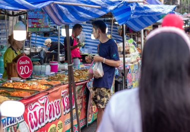 Suratthani, Tayland - 21 Nisan 2024: Yemek ve sebze almak için sokaklarda yürüyen insanlar, hem Tayland 'ın şehir ve kırsal kesimlerinde hem de sokak yemeklerinde yol kenarında satılıyor.