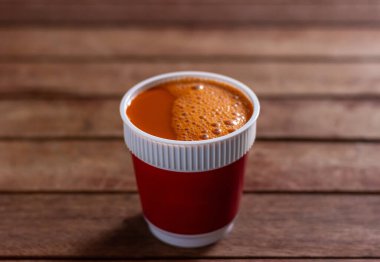 Tahta masada beyaz bir fincanda sıcak süt çayı bulanık arka plan